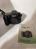 Canon EOS 30D camera body alongside its user manual on a white surface.