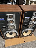 Pair of JVC SK-S66 4-way stereo speakers with wood veneer finish, front view showing woofer, midrange, and tweeters.