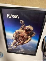 Framed artwork of NASA astronaut in space with Earth backdrop