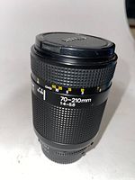 Nikon Nikkor 70-210mm f/4-5.6 autofocus lens upright showing focal length and aperture markings with lens caps on both sides.