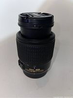 Front view of the Nikon Nikkor 55-200mm DX lens with lens cap attached, showing the textured zoom grip and branding.