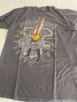 Full view of gray Paul McCartney t-shirt with front graphic featuring Paul McCartney playing guitar and performing. Shows the full design and shirt shape.