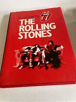 Front cover of the book showing title, band members, and tongue logo on a red background.