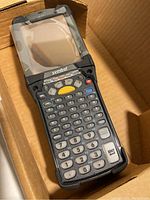 Photo of Symbol MC9090 handheld barcode reader in a box, showing keypad, screen area, and physical condition.