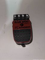 Photo showing the Washburn Bad Dog Stereo Flanger guitar effects pedal with four knobs and red metal casing.