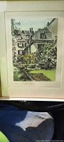 Image of framed colored block print showing a residential scene with houses and garden greenery, framed and matted.