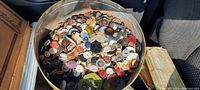 Top view of round vintage tin filled with many assorted antique buttons of different sizes, shapes, and colors