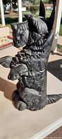 Left side view of the cast iron Scottish Terrier door stop showing detailed fur texture and dog's mouth holding a rectangular block.