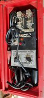 Photo showing the red plastic case open with the coil and condenser tester unit, wiring, clamps, and control knobs.
