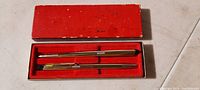 Vintage pen and pencil set in original red box with red velvet interior showing two goldtone writing instruments.