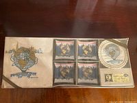 Original packaging showing four trays and packs of coasters and napkins with the Unisphere and New York skyline design.