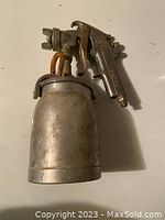 Full side view of the Astro AS8 paint pot spray gun showing the metal container and trigger mechanism.