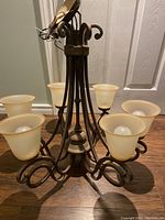 Front and angled view showing the full metal frame and five frosted glass shades with bulbs installed.