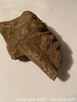 Photo showing side view of the rock with pointed inclusion and rough texture.