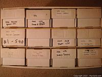 Wide view of multiple cardboard boxes labeled with different NFL and MLB card sets, showing organized collection.