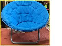 Blue moon saucer chair angled view showing blue fabric and metal frame on carpeted floor.