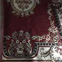 Rug showing detailed corner with floral patterns in red, beige, and black
