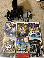 Full set including console, power adapter, video RCA cable, Wii stand, black Wii remote and Nunchuk controllers, plus six Wii game cases.