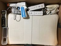 Photo showing Wii Balance Board with remotes, nunchuks, and Nyko Perfect Shot light gun.
