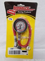Longacre analog tire pressure gauge in original packaging, showing 2 inch dial with 0-15 psi range, attached red hose, and metal connector fitting