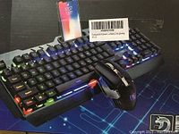 Wireless mechanical feel RGB keyboard and gaming mouse with smartphone for scale, showing keyboard backlight colors and mouse design.