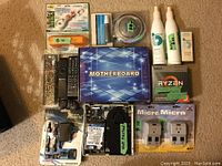 Image showing a variety of electronic and personal care items including boxed motherboard, Ryzen CPU box, remote controls, hard drive with fan, chargers and adapters, and electrical outlet covers.