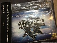 Overall front view of the unopened WrestleMania XX 20th Anniversary pin collection in sealed plastic bag with black header card and $49.97 price visible.