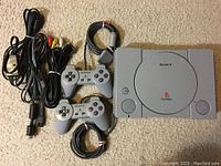 Full lot overview showing console, two controllers, AV and power cables on beige carpet