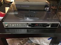 Top view of Sansui P-L51 turntable with dust cover closed and front control panel showing numbered buttons for random access programming.