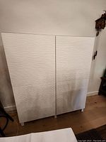 Front view of white storage cabinet with two wave-textured doors