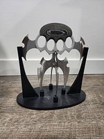 Front view of fantasy blade interceptor on black oval display stand showing the four main curved stainless steel blades and two side blades with Spanish Micarta handle.