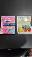 Photo showing two books: "Guide to Fashion Sewing" with colorful abstract fabric design on cover and "Making Leather Handbags" with various leather handbags on cover.