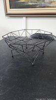 Black wireframe fruit basket showing geometric design and elevated metal feet