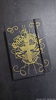 Closed view of black Bible-style book with gold religious design on cover