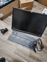 HP ZR24w monitor showing front side with power cord and one wall mount on floor next to it.