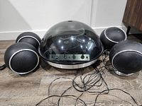 Front view of Electrohome Apollo record player with four spherical speakers and tangled cords on a wood floor