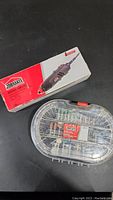 Photo shows Jobmate rotary tool in original box next to a clear plastic organizer case containing various rotary tool accessories neatly arranged.