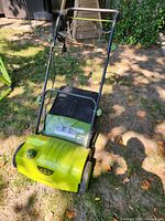 Overall view of the Sun Joe electric dethatcher in outdoor grass setting showing the body, wheels, and handle.