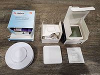 Overview of the lot with the Zigbee Smart Air Box, Tuya Smart Gateway, instruction manual, and original packaging on a wooden table.