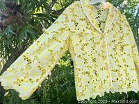 Front view of yellow cotton eyelet lace jacket with white piping and scalloped hem and sleeves.