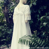 Rear view of vintage wedding dress showing the back bow, lace-trimmed mid sleeves, and flowing fabric