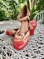 Side angle showing the profile of one shoe and the heel height and design with pink and beige leather with striped accents.