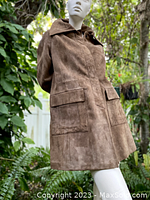Side angle view of the brown suede coat on mannequin outdoors showing collar, pockets, and texture.