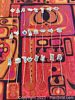 Full set of 24 silver appetizer forks with abalone inlay tops arranged on fabric.