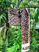 Photo of vintage large fake leopard fur purse hanging outside with leopard print scarf draped next to it showing pattern and size.