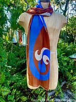 Scarves draped on mannequin showing full length and color scheme of mid century stylized bird design in blue and brown tones.