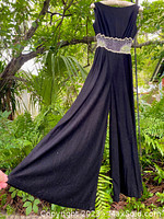 Full view of black jumpsuit showing extremely wide palazzo pant legs and silver rhinestone mesh midriff detail