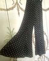 Full length view of black polka dot polyester palazzo pants highlighting extreme bell bottom flare and fabric pattern.