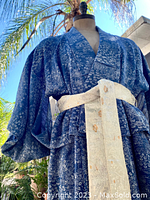 Close-up side view of the blue crepe kimono showing fabric texture and pattern along with the brocade ivory gold sash tied at the waist.