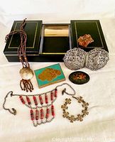 Full lot overview showing the leather jewelry box, loose stone, necklaces, European change box, Russian lacquer pin, metal belt buckle, and brass bracelet.